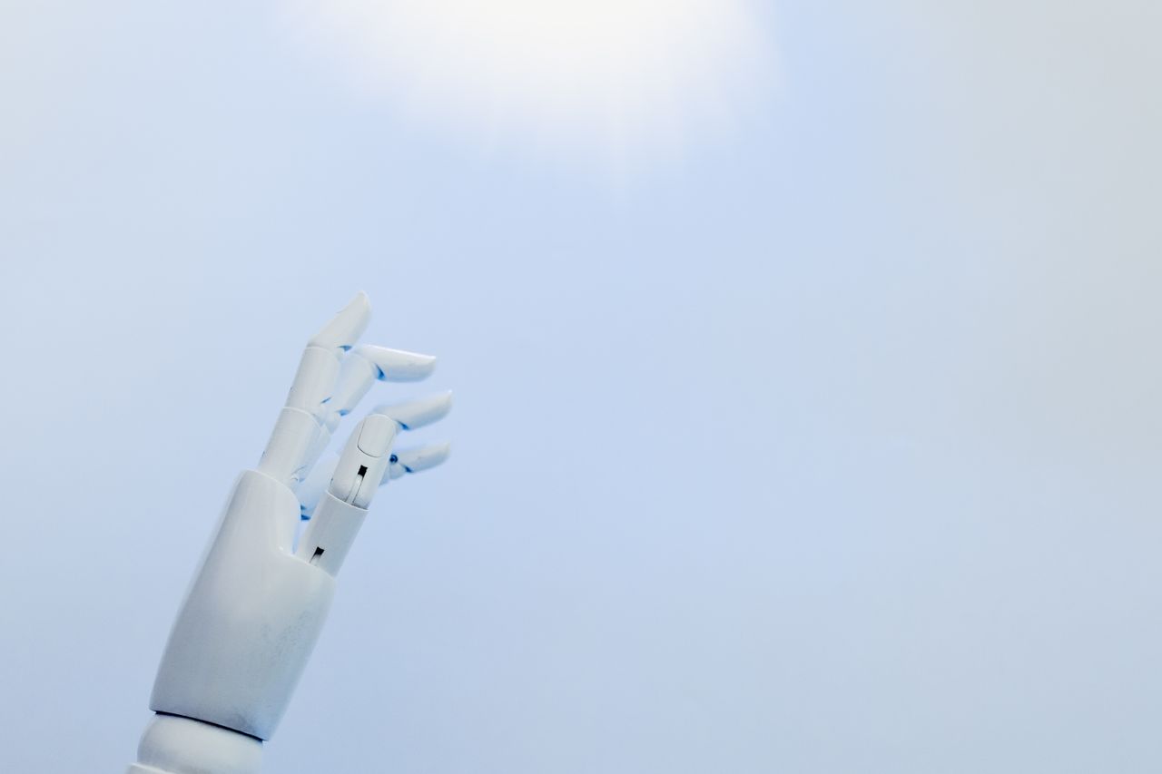 services-02 A robotic hand reaching towards a bright light on a white background symbolizing innovation.