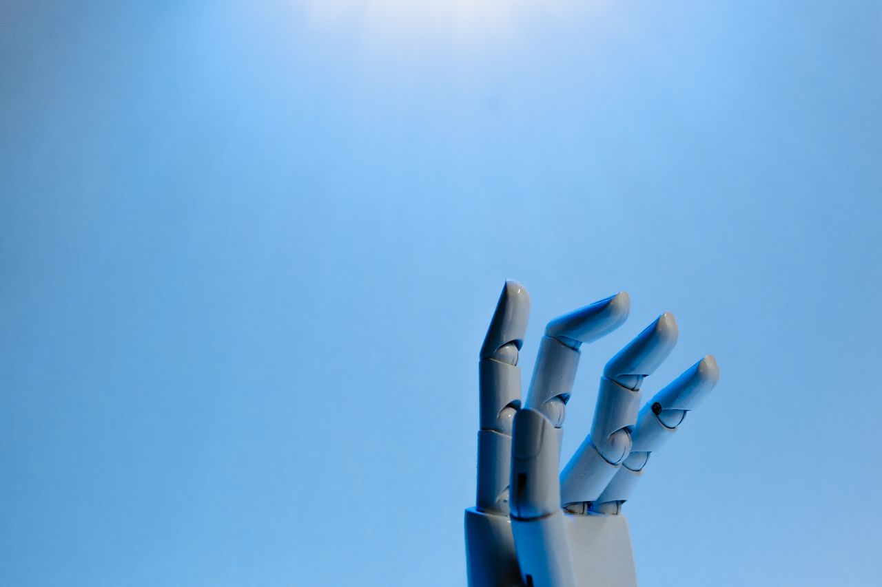 Mastering the First Impression: Your intriguing post title goes here Robotic hand with articulated fingers reaching towards the sky on a blue background.